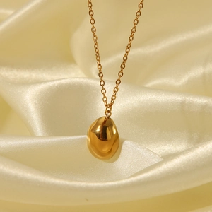Elegante collana dorata con ciondolo a fagiolo ovale su sfondo di raso beige seta