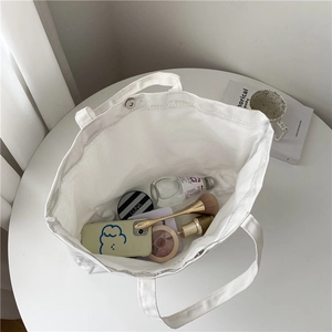 White canvas tote bag with interior view showing large capacity and magnetic buckle closure