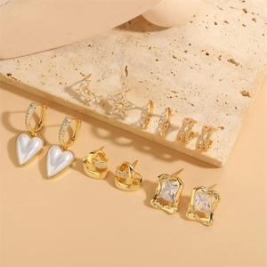 14K gold plated heart and star earring set with zircon and pearls on stone surface