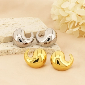 Macro view of gold and silver comma shaped stainless steel earrings on stone