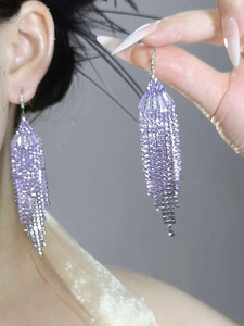 Close-up of purple zircon tassel earrings with shiny fan-shaped crystal fringe details
