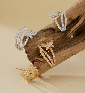 Detailed view of zircon-encrusted butterfly earrings displayed on natural wood