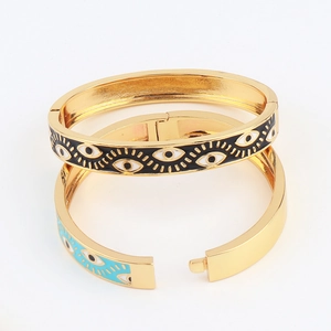 Gold-plated hip hop evil eye bracelets with black and blue enamel charms on white background