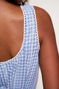 Detail of blue gingham dress with white scallop lace trim on the shoulder straps