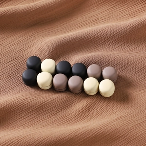 Matte magnetic scarf clips in neutral colors organized on brown fabric surface