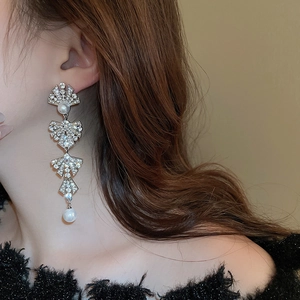 Macro detail of silver tassel earrings with pearls and rhinestones on model side profile
