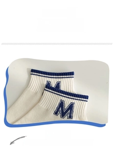 Detail of white cotton ankle sock featuring blue stripes and embroidered letter M