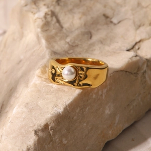 Detail of 18K gold-plated lava textured ring with white pearl on natural stone