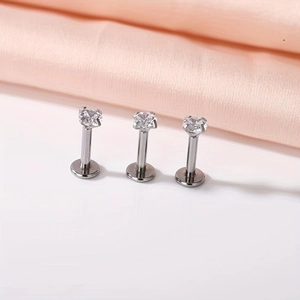 Three silver labret studs with cubic zirconia crystals on pink silk background