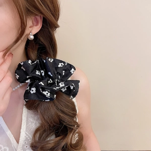 Floral print black fabric scrunchie detail on wavy brown hair with soft lighting