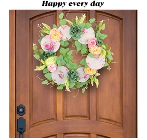 Detail of floral wreath on dark wood door with pink roses and ceramic pattern discs