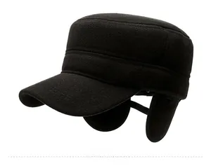 Detail of black winter flat top hat featuring foldable ear flaps and metal badge