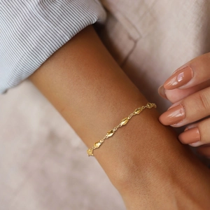 Detailed view of minimalist 18K gold star bracelet on wrist with elegant droplet links