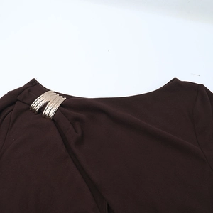 Détail de l'attache en métal doré sur une robe en maille marron foncé avec découpe