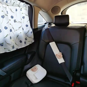 Plush bear tissue box and floral sunshade displayed on a car seat in a cozy interior