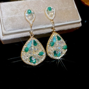 Gros plan de boucles d'oreilles vintage dorées avec cristaux verts sur boîte à bijoux