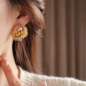 Boucles d'oreilles vintage de luxe avec tressage doré perles et pierres jaunes sur mannequin