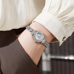 Detail showing a silver ladies watch with crystal inlay and Arabic numerals on a white dial