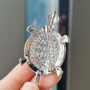 Macro shot of the silver turtle brooch back showing the pin closure and textured metal