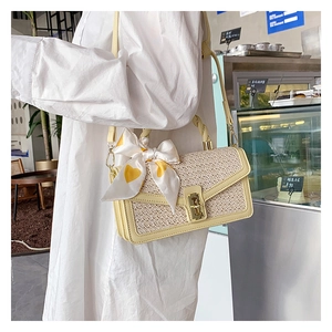 Detail of woven beige straw bag with yellow PU leather trim and heart print scarf