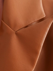 Detailed macro view of the brown PU leather blazer's lapel and fine pebble grain texture