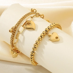 Close-up of double-layer 18K gold plated steel heart bracelets on elegant white pedestal
