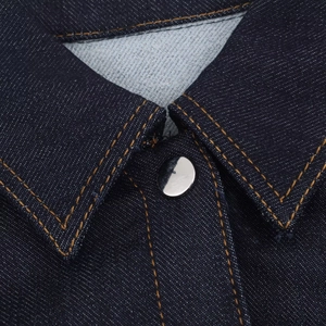 Détail du col d'une robe en denim bleu foncé avec boutons métalliques et surpiqûres