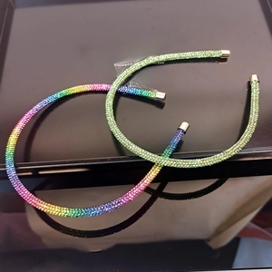 Close-up of thin rainbow and gradient green rhinestone headbands with gold tips