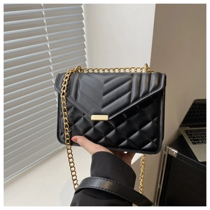 Detail of black V-quilted leather shoulder bag with gold chain strap and metal lock