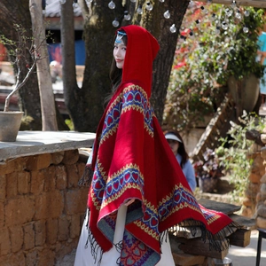 Détail d'un poncho en tricot rouge ethnique avec motifs de cœurs et bordures à franges
