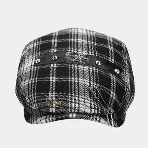 Detail of plaid beret hat with metallic rivets, silver star emblem and punk pins