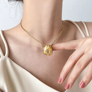 Detail of gold lava textured necklace with clear zircon stone worn on a model