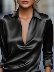 Detail einer eleganten schwarzen Satinbluse mit V-Ausschnitt und seidiger Textur