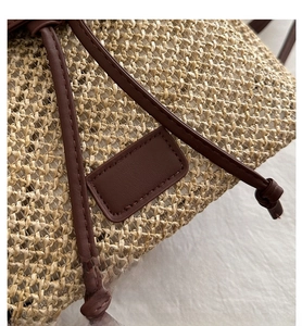 Detail view of natural straw weaving texture and premium brown leather drawstring closure