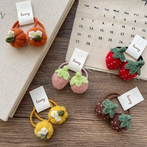 Cute knitted strawberry and pumpkin hair ties for girls on a wooden background