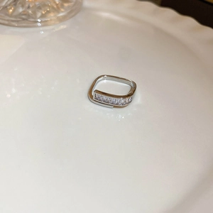 Gros plan d'une bague géométrique argentée sertie de zircons sur un plat en céramique