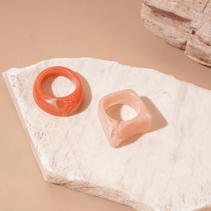 Detailed macro of coral orange and pale pink marble resin geometric acrylic rings