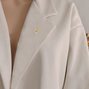 Elegant gold wheat ear brooch pin with crystals on a white blazer lapel for women
