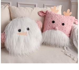 Detailed view of plush Santa Claus and reindeer pillows on a cozy beige sofa