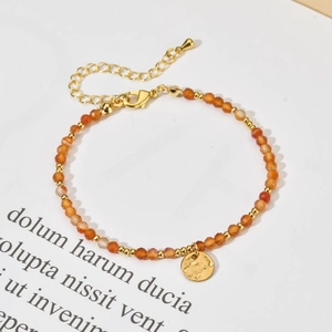 Detail of natural orange stone beaded bracelet with hammered gold metal charm and lobster clasp