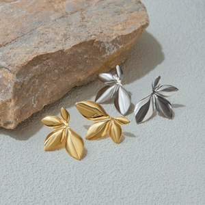 Detailed view of gold and silver leaf earrings on a stone base for a premium texture