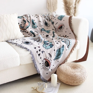 Close-up of Bohemian evil eye knit throw blanket with tassels on a white sofa