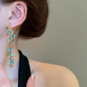 Dettaglio degli orecchini a nappa in oro 18k con perle di vetro blu indossati