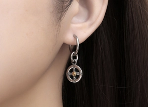 Close-up of a punk style hoop earring with cross pattern pendant and gold detail