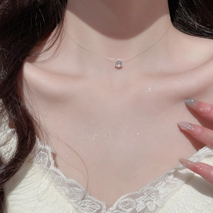 Primo piano di collana invisibile in filo da pesca con ciondolo in zircone su collo donna