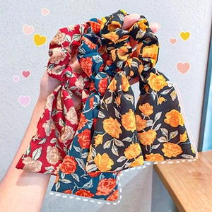 Close-up of floral print hair scrunchies with streamers in red, navy, and black patterns