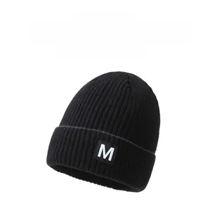 Detail showing thick black ribbed knit beanie texture and white letter M patch detail
