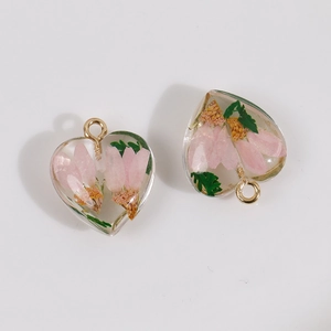 Detail of heart-shaped resin pendants with pink dried flowers and gold metal rings