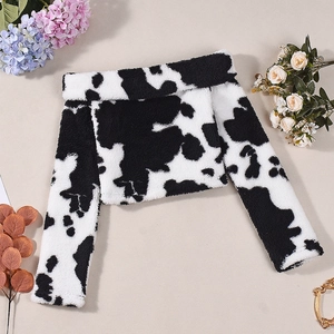 Detail shot of black and white cow print plush cropped shrug top on floral background