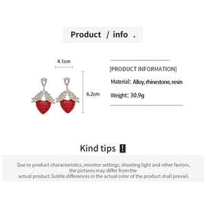 Detail view of red heart and rhinestone wing earrings with size dimensions 4.1cm by 6.2cm